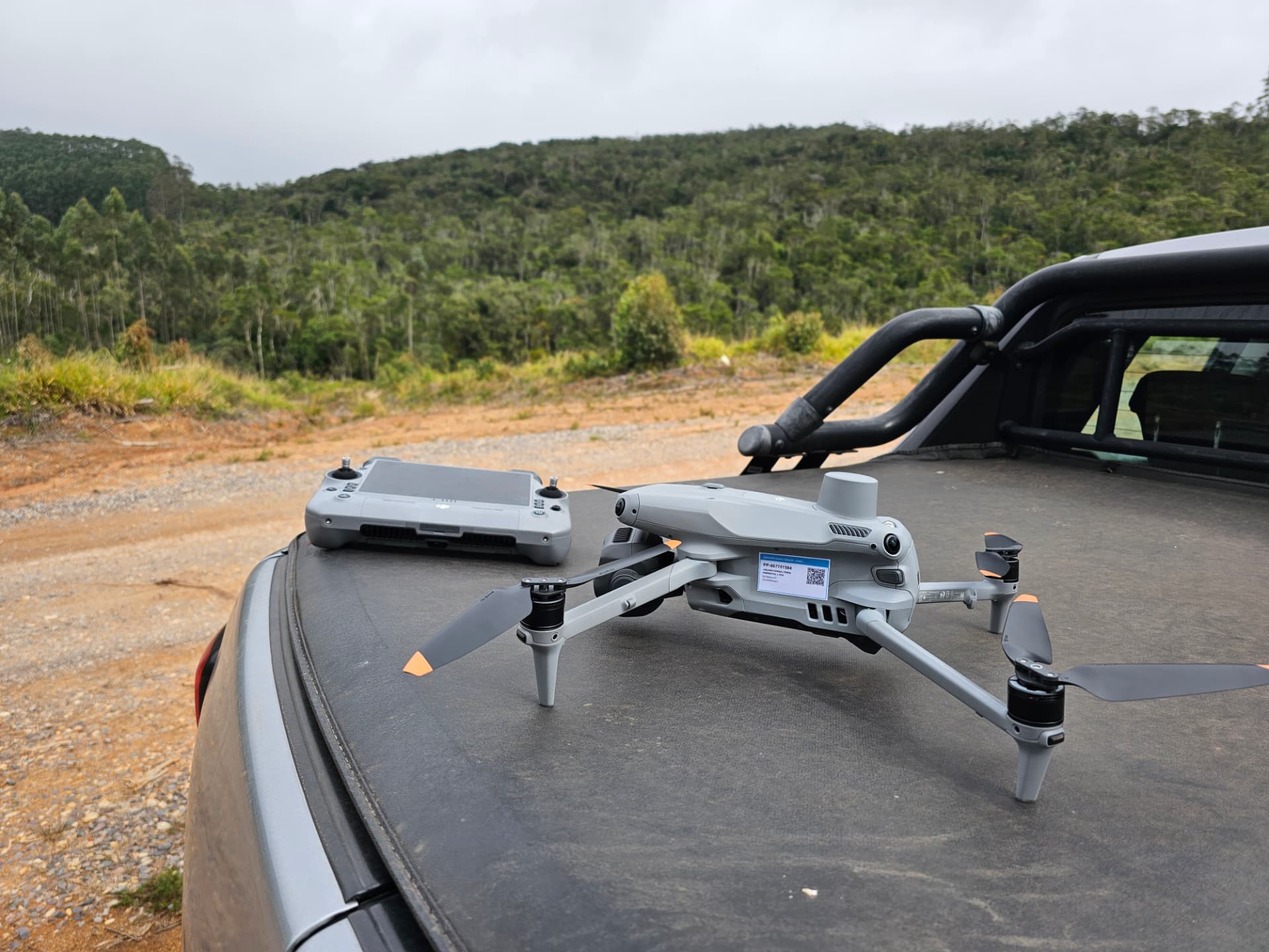 Drone DJI Matrice 4T com controle remoto em operação de campo, com área florestal ao fundo